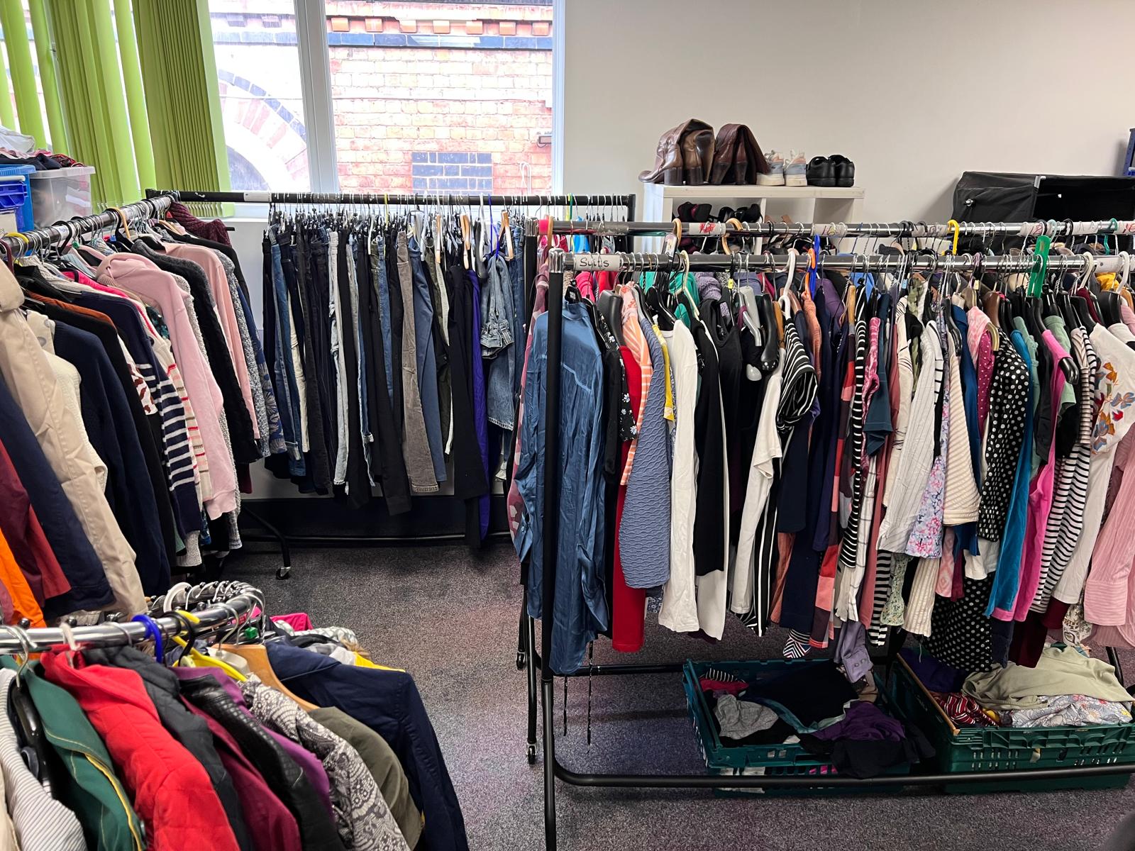 Rails of donated clothes on hangers in the clothing room.