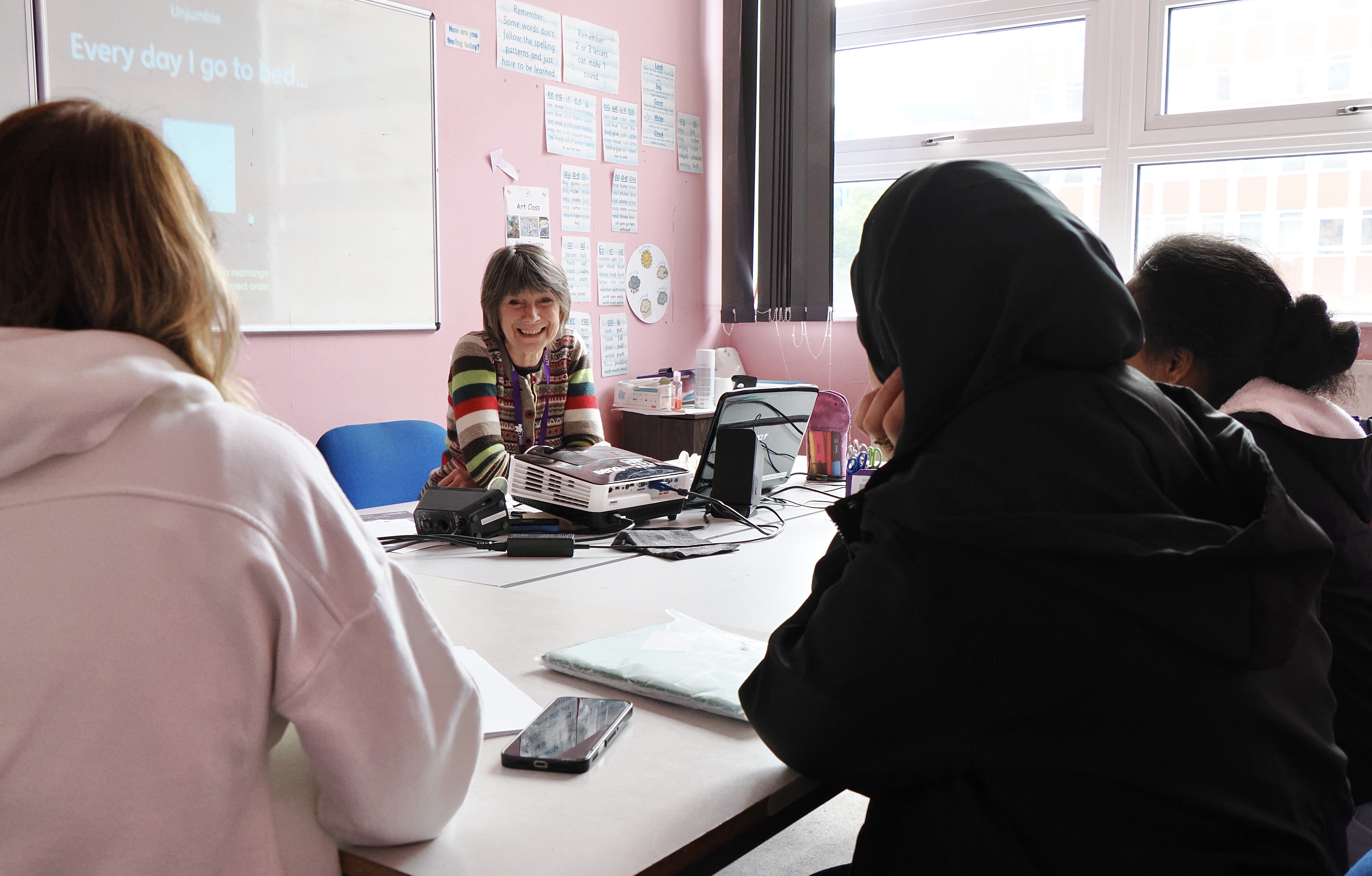 A volunteer teacher smiling at the front of an English class.