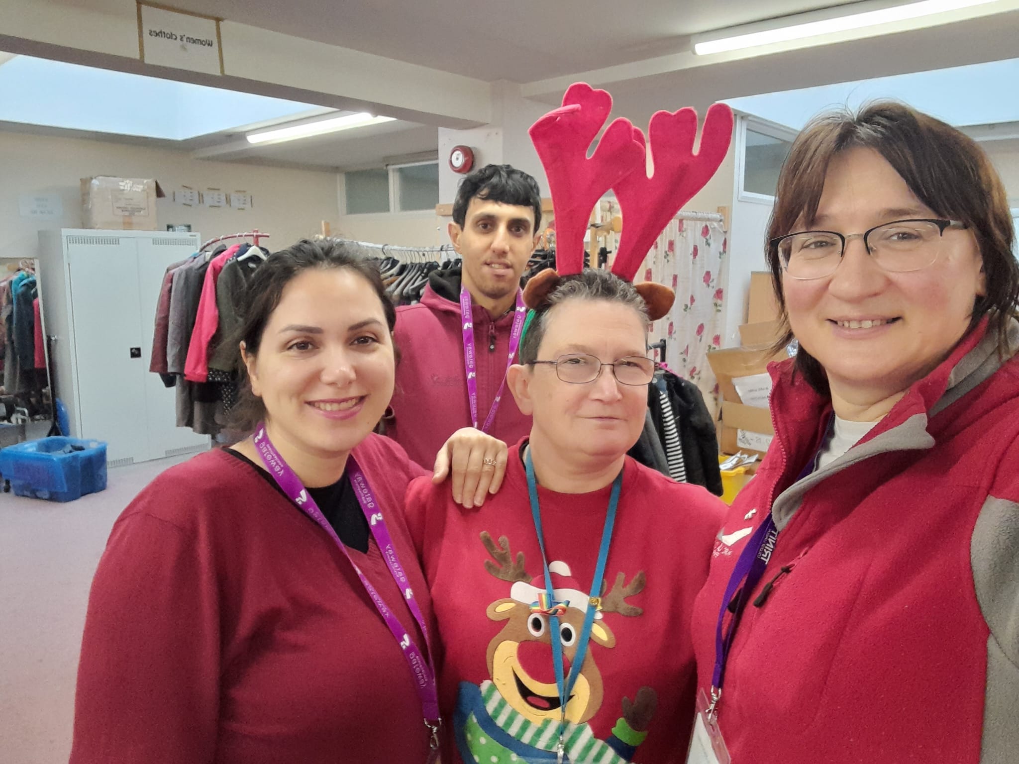 Four volunteers in red jumpers at Christmas, one wearing reindeer antlers.
