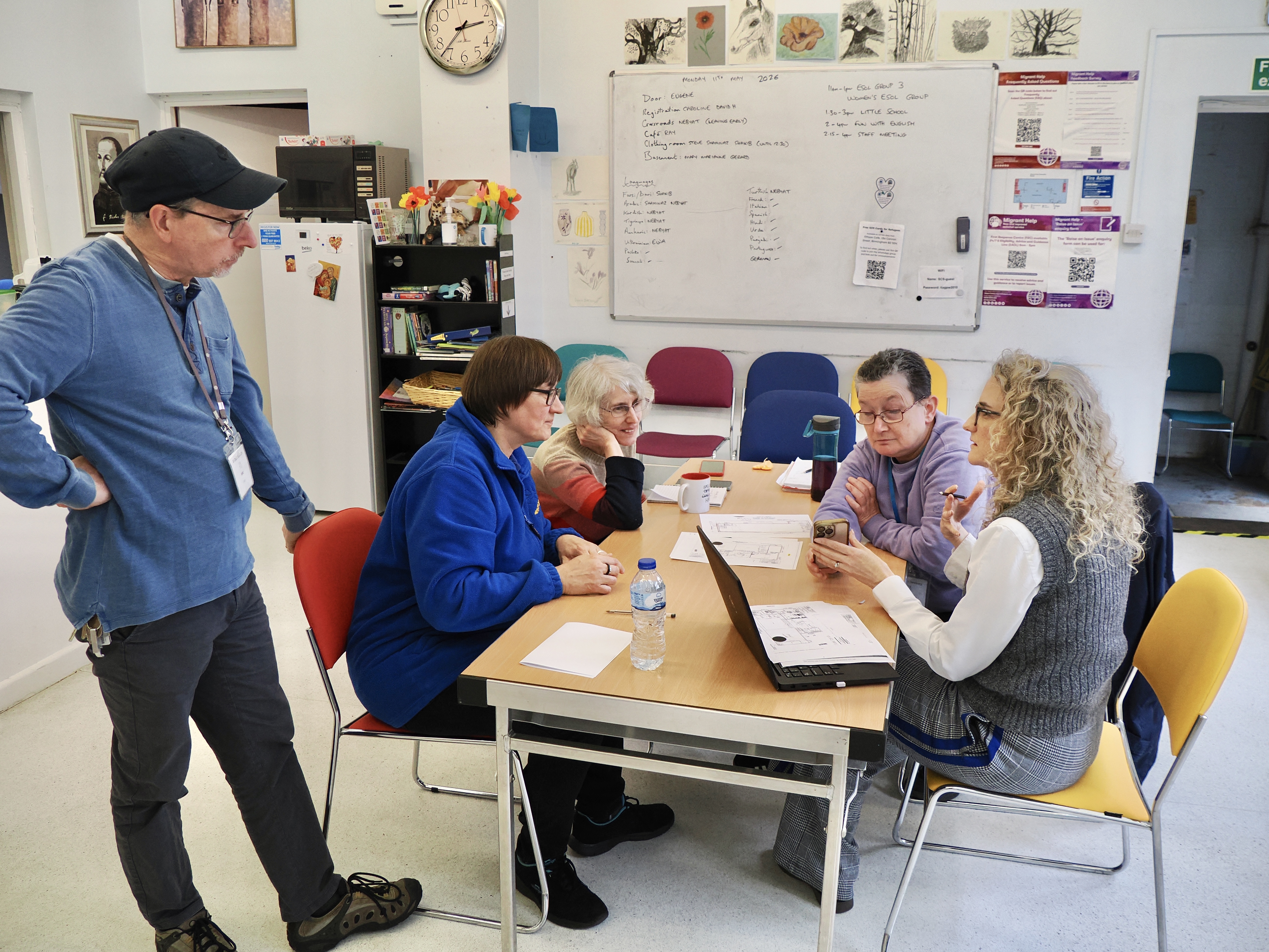 Volunteers and staff working together around a table with laptops and paperwork.